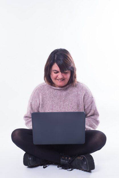 Mujer sentada mirando su computadora portátil sobre fondo blanco. Concepto de compra online. Dupdo