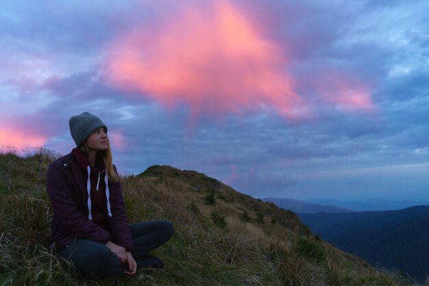 La mujer sentada en la montaña en el fondo radiante