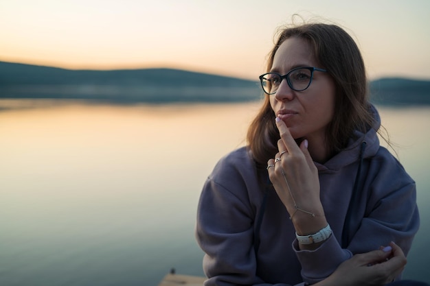 Mujer sentada en el muelle retrato de primer plano puesta de sol de verano