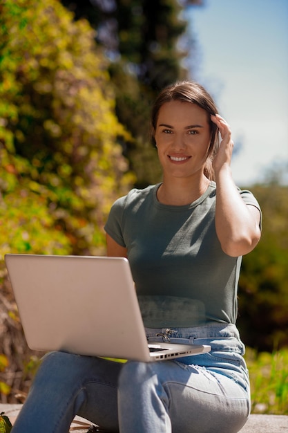 Mujer sentada en el parl y trabajando en una computadora portátil
