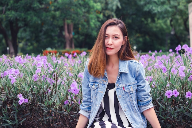 Mujer sentada en un parque donde las flores florecen maravillosamente.