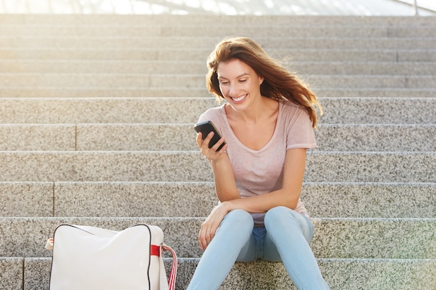 Mujer sentada en pasos y mirando el teléfono inteligente