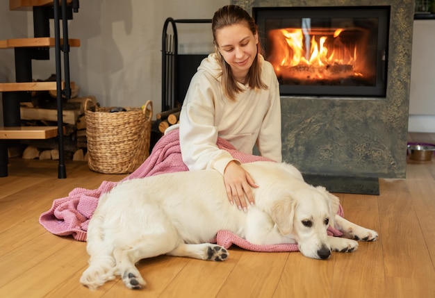 Mujer sentada con el perro cerca de la chimenea