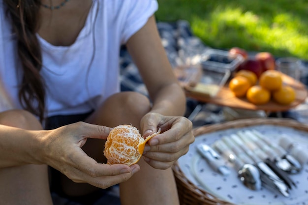 Mujer sentada en un picnic comiendo una mandarina