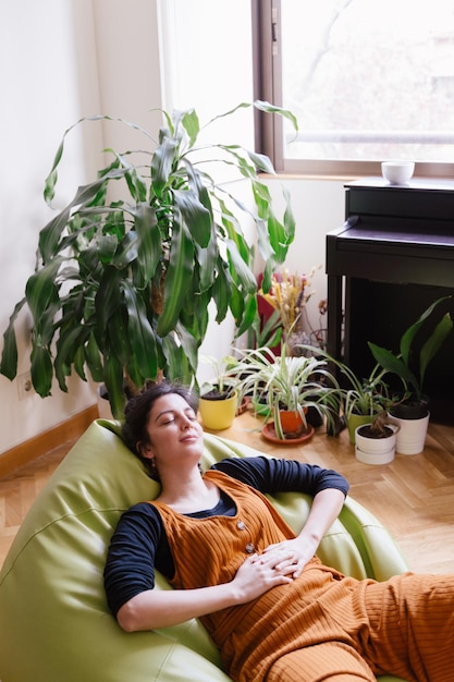 Foto mujer sentada en una planta en maceta en casa