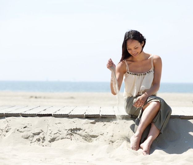 Mujer sentada en la playa con arena en la mano