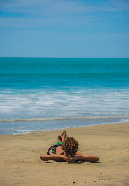 Foto mujer sentada en la playa contra el cielo