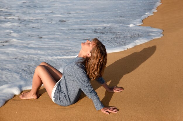 Mujer sentada en la playa y disfrutando de su tiempo