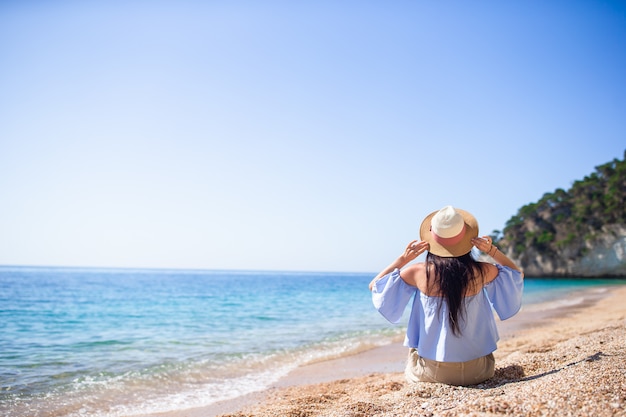 Mujer sentada en la playa disfrutando de las vacaciones de verano mirando al mar