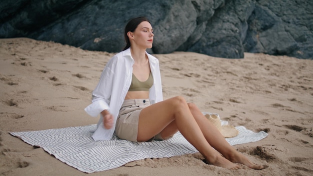 Mujer sentada en una playa de mantas mirando el paisaje marino chica tranquila relajándose en una cubierta