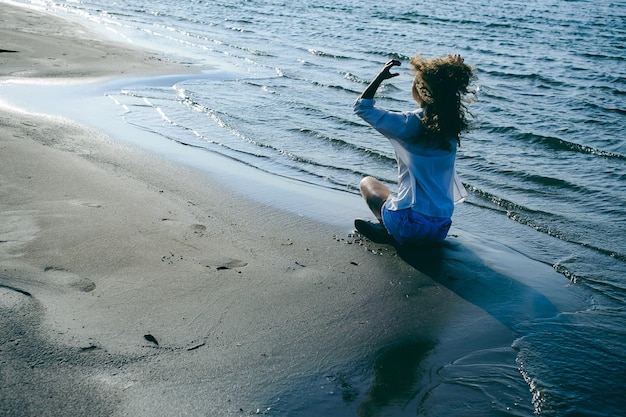 Foto mujer sentada en la playa