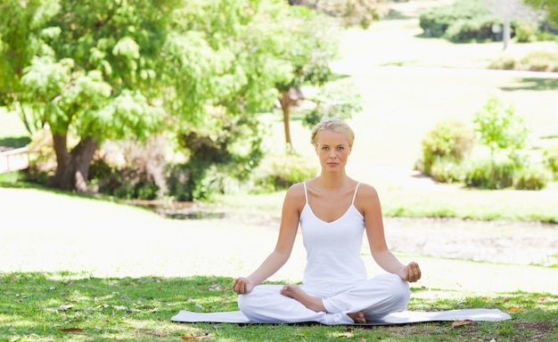 Mujer sentada en posición de yoga en el parque