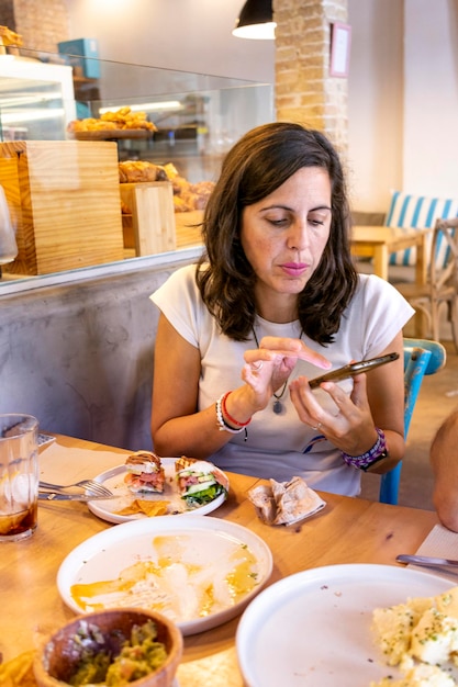 Mujer sentada en el restaurante usando un teléfono celular para enviar mensajes de texto