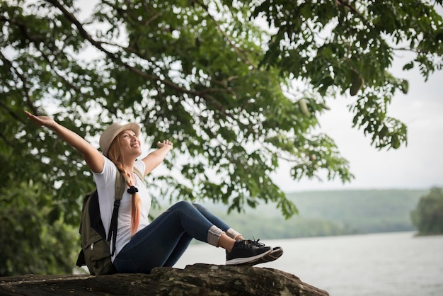 Foto mujer sentada en una roca junto al lago contra el cielo