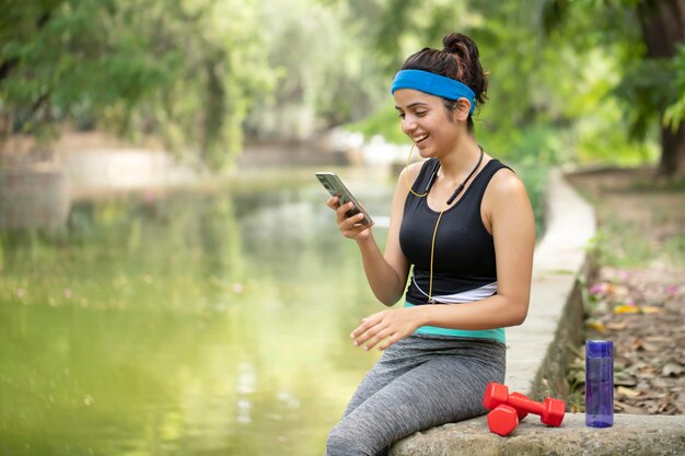 Foto una mujer está sentada en una roca y mirando su teléfono