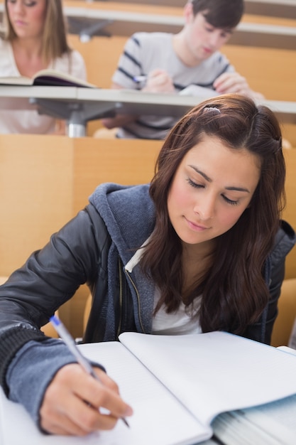 Mujer sentada en la sala de conferencias escribiendo