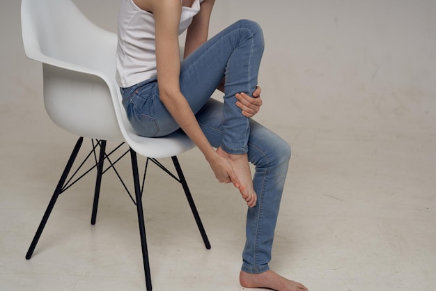 Mujer sentada en una silla y dolor en la pierna problemas de salud articular foto de alta calidad