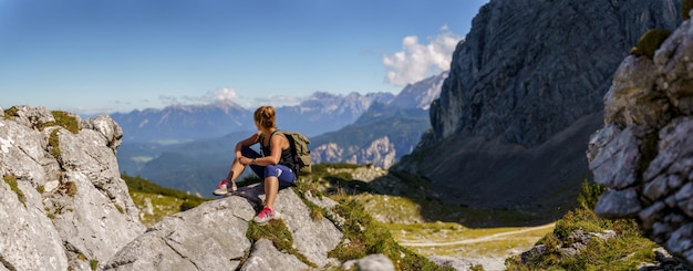 Mujer sentada sobre una pequeña colina en un hermoso paisaje de montaña