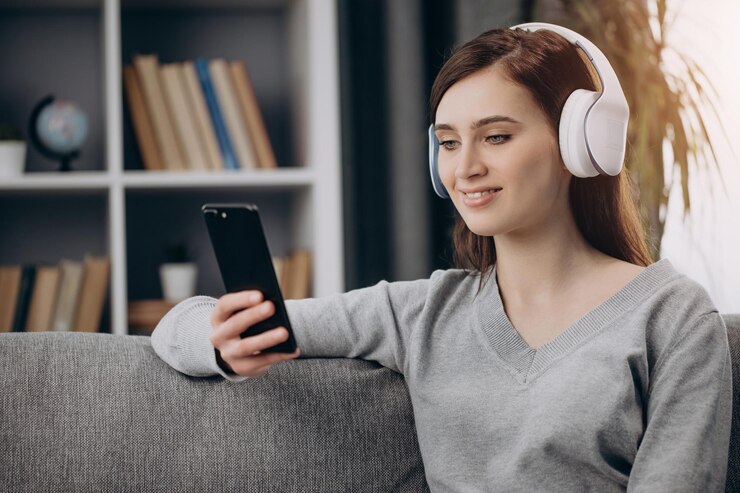 Mujer sentada en el sofá con auriculares y escuchando música