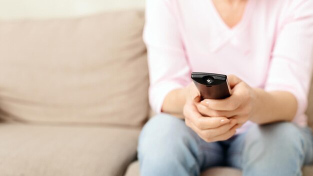 Foto una mujer sentada en un sofá beige con un control remoto