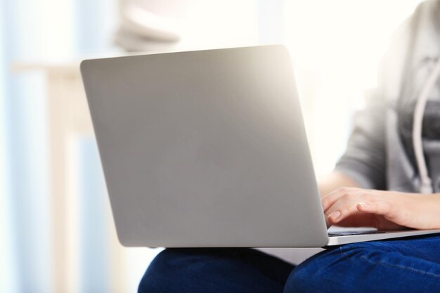 Mujer sentada en el sofá con una computadora portátil en una habitación