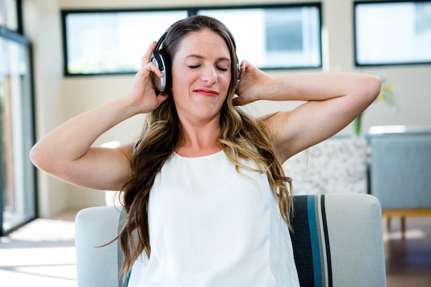 Mujer sentada en el sofá escuchando música en sus auriculares