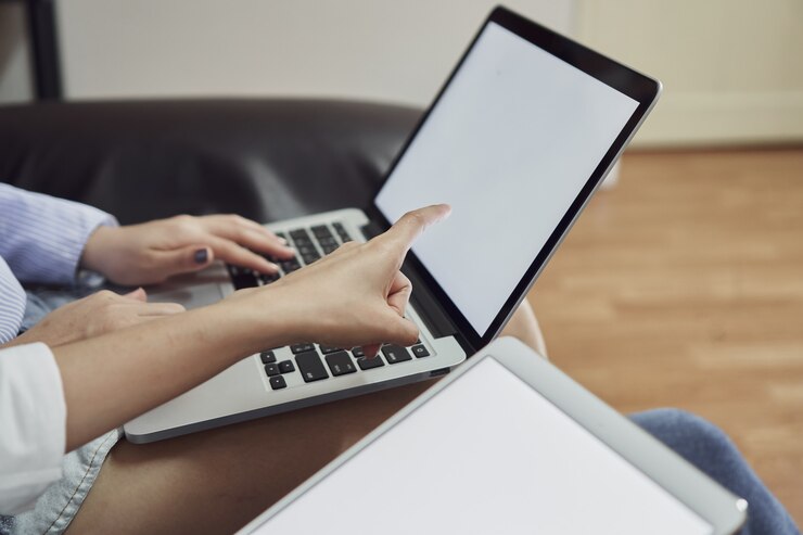 Foto mujer sentada en un sofá negro con computadora y tableta de pantalla en blanco. pantalla en blanco para la g