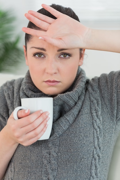 Mujer sentada en el sofá y sentirse enfermo