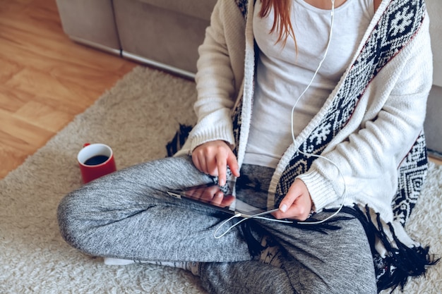 Mujer sentada en el sofá con tableta y café en la mano