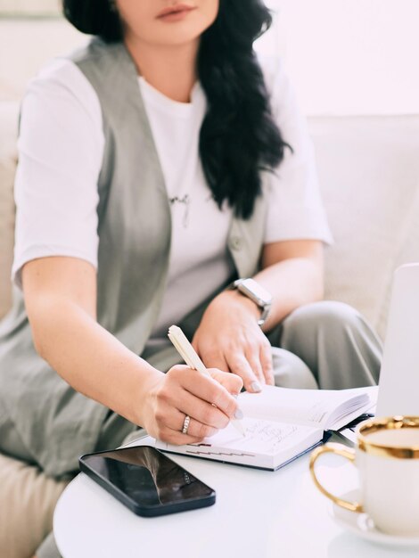 mujer sentada en el sofá y tomando notas en su cuaderno Educación analítica empresarial