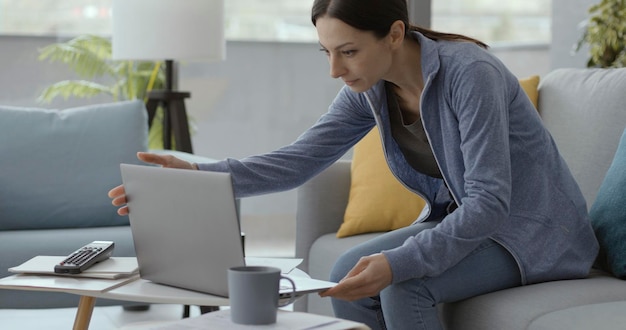 Mujer sentada en el sofá y usando su computadora portátil