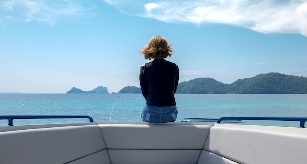 Una mujer sentada sola en un bote mirando el horizonte.