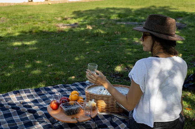 Mujer sentada con sombrero en un picnic en el parque