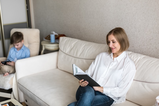 Foto la mujer está sentada sosteniendo un libro en la mano y leyendo.