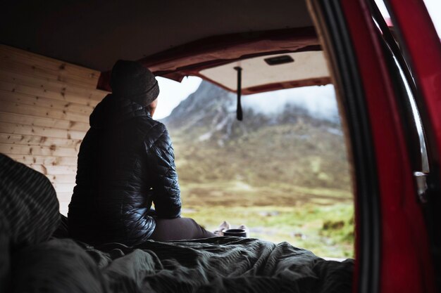 Mujer sentada en su autocaravana mirando las montañas