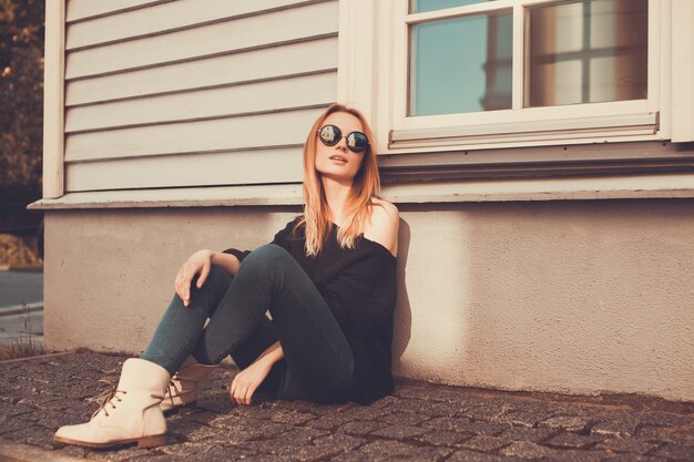 Mujer sentada en el suelo con gafas de sol