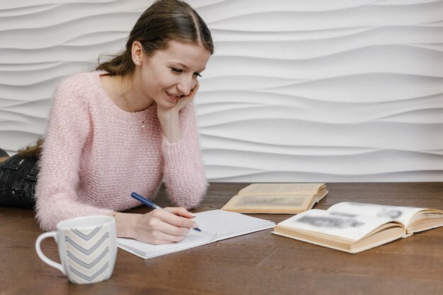 Foto mujer sentada en el suelo y libro de lectura