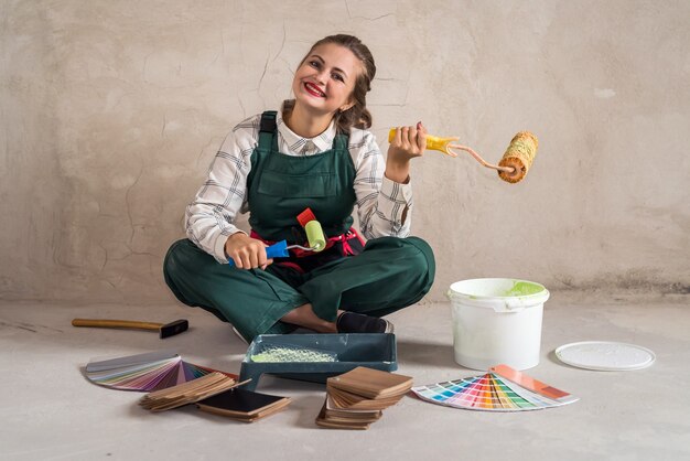 Mujer sentada en el suelo y posando con herramientas de pintura