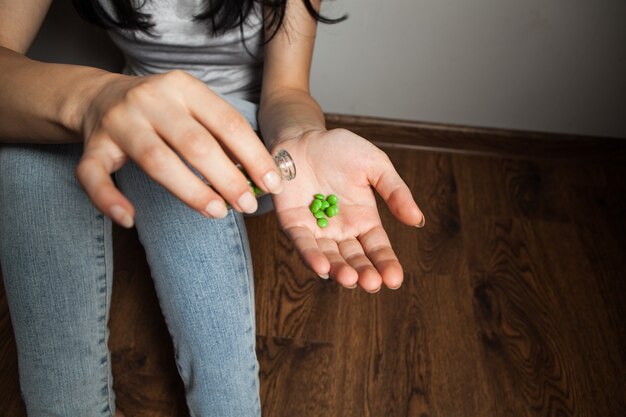 Mujer sentada en el suelo sosteniendo pastillas