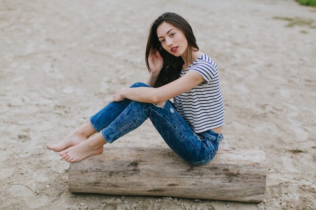 mujer sentada en un tronco en la playa