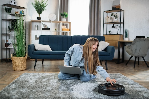 Mujer sentada usando una aspiradora robot para el hogar