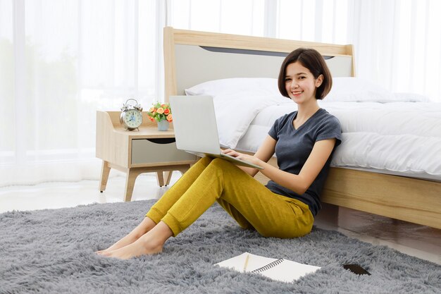 Mujer sentada y usando la computadora en el dormitorio