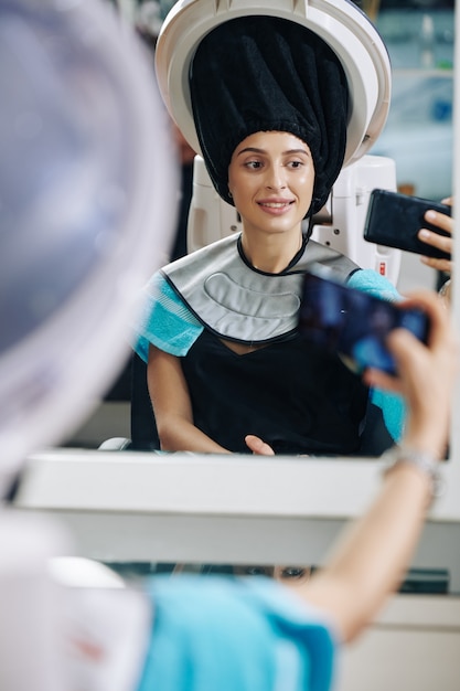 Mujer sentada bajo el vaporizador de pelo