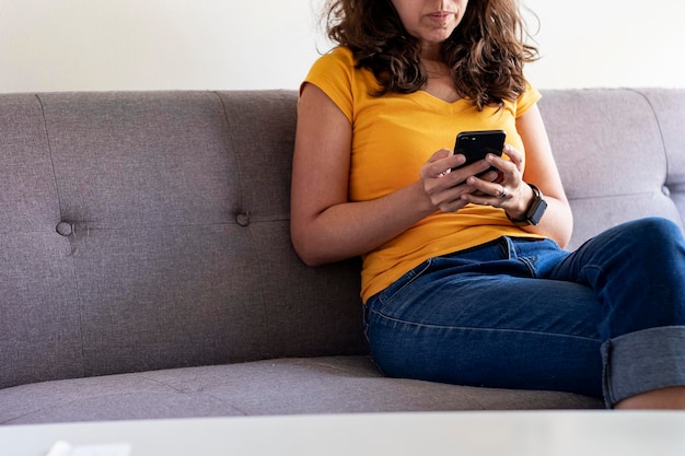 mujer se sentar, en, sofá, con, teléfono celular, en, mano