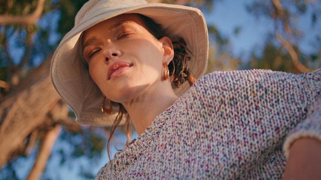 Mujer serena cerrando los ojos a la luz del sol primer plano tranquila hermosa modelo en el jardín