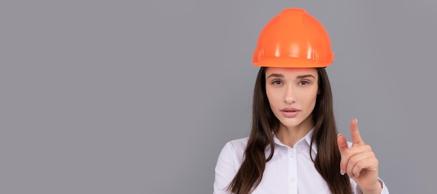 Mujer seria jefa en casco protector y camisa blanca señalando con el dedo a la cámara jefa mujer