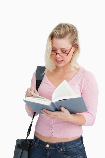 Mujer seria leyendo una novela mientras usa gafas