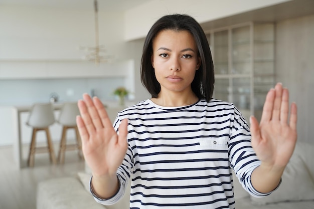 Mujer seria que muestra un gesto de parada de mano protestando contra el abuso de violencia doméstica o el aborto