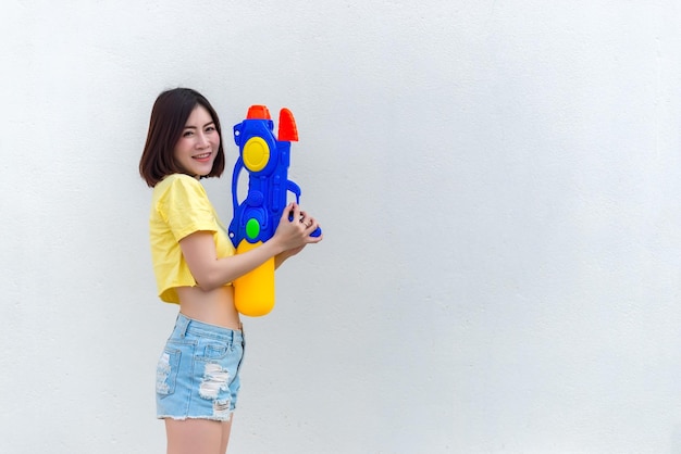 Mujer sexy asiática con agua en la mano sobre fondo blancoDía del festival songkran en tailandiaLo mejor del festival de tailandiaTierra de la sonrisa