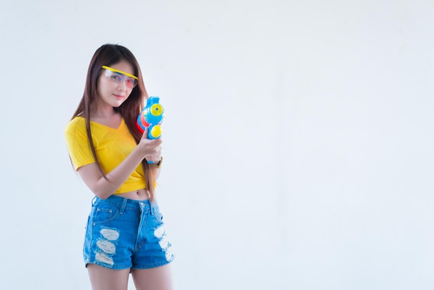 Mujer sexy asiática con agua de pistola en la mano sobre fondo blancoDía del festival songkran en tailandiaLo mejor del festival de tailandiaTierra de la sonrisa
